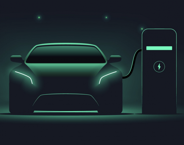 Ein Elektroauto, das gerade an einer Ladestation lädt. Sehr dunkles Bild, das Auto schimmert in grünen Farben.